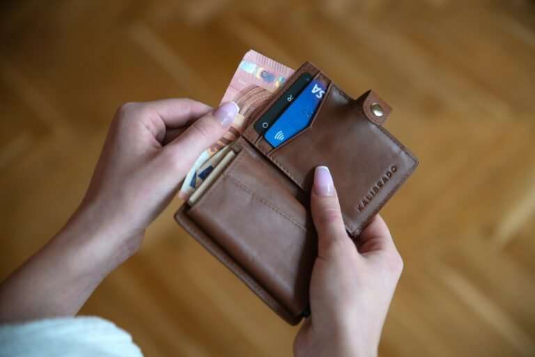 Person holding a leather card wallet with a UK credit card, representing rewards credit cards in the UK